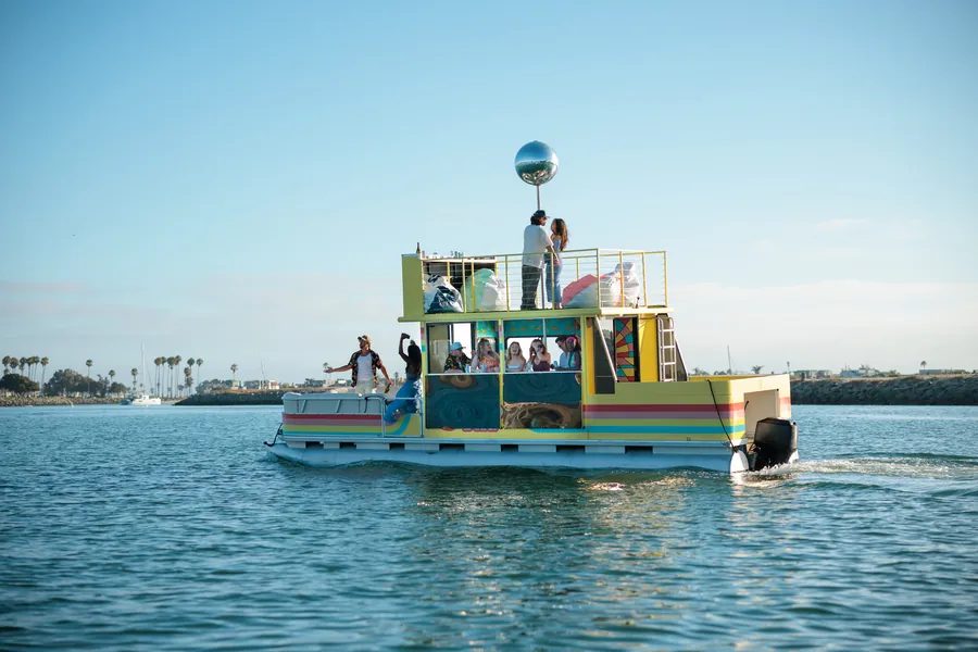 Disco Boat cruising on San Diego Bay at golden hour with guests on the rooftop